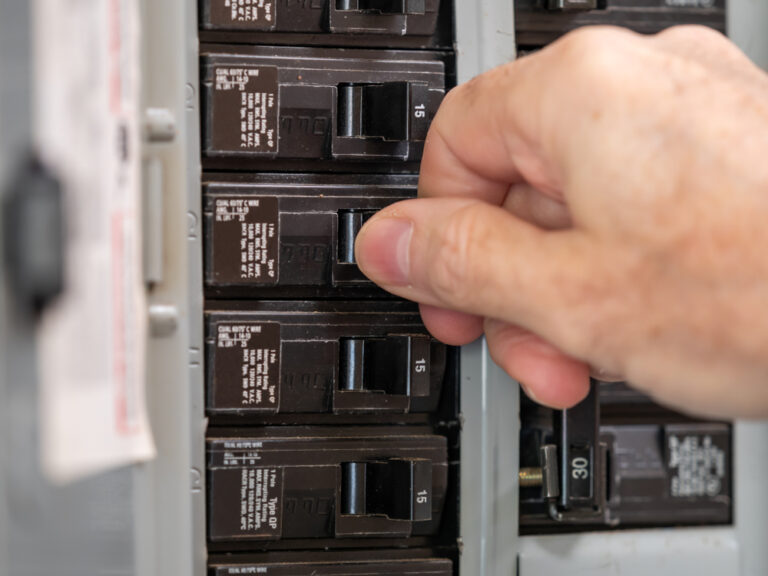 male electrician's hand flipping a circuit breaker
