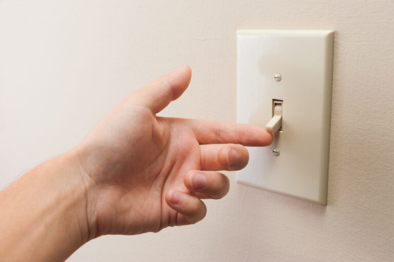 hand turning on a light switch during a home inspection before buying a house
